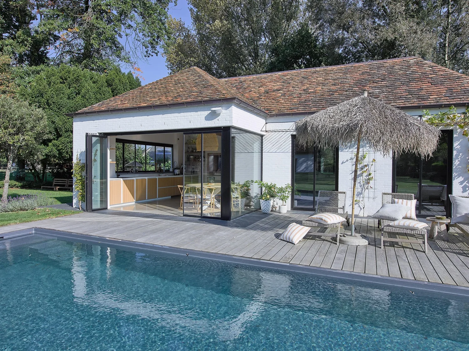 Wit poolhouse met pannendak aan een zwembad in Sint-Gillis, met een draaibare schuifwand met dubbel glas