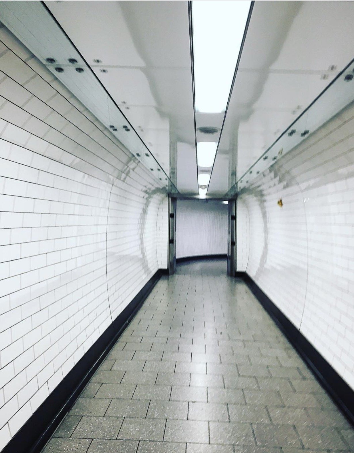 A slightly blurred empty tiled passage bending out of sight