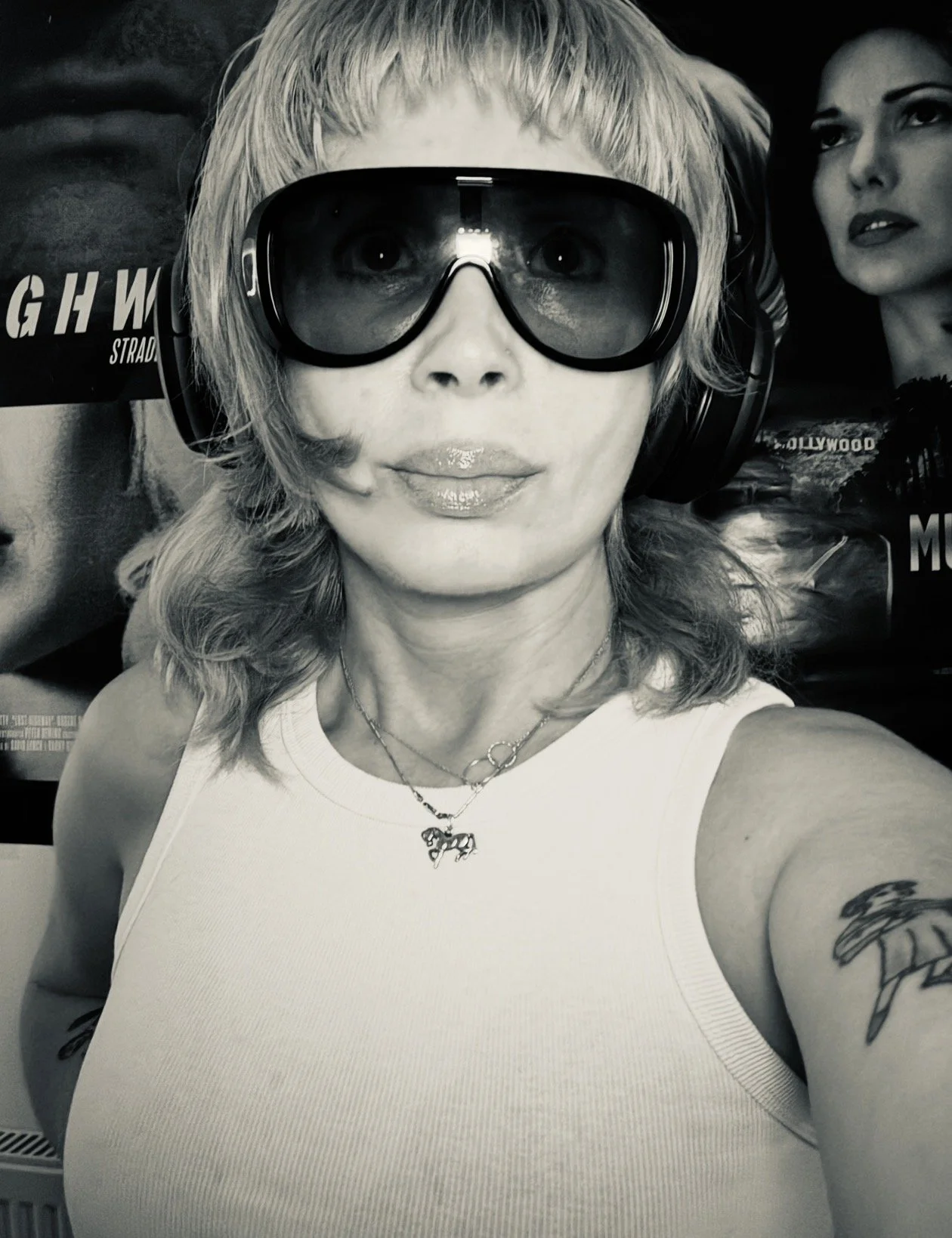 Lena Vers wearing sunglasses and headphones in front of film posters