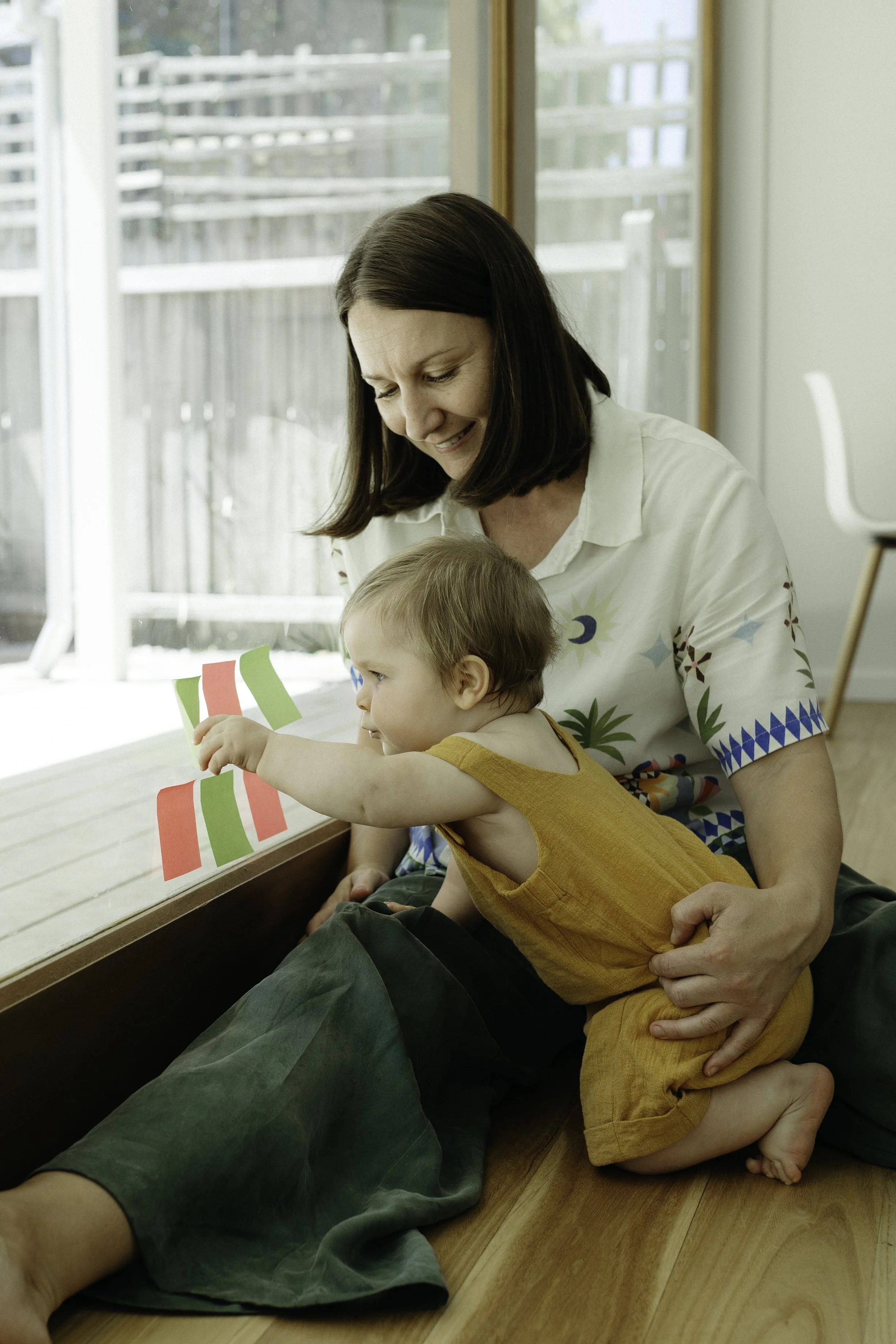 Nicole Pates playing with a baby by a sunny window