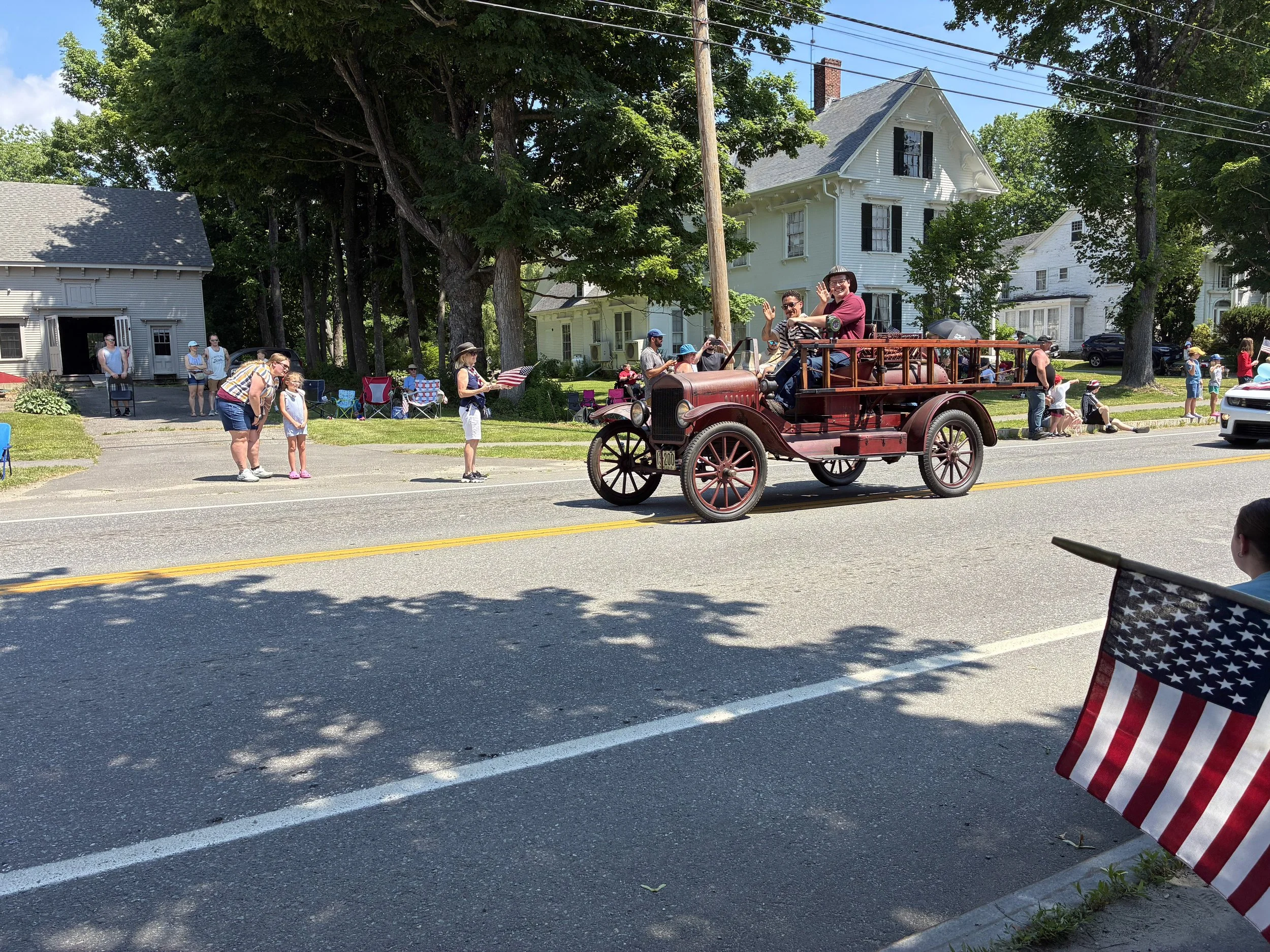 An antique fire truck rolls by in a small-town parade.
