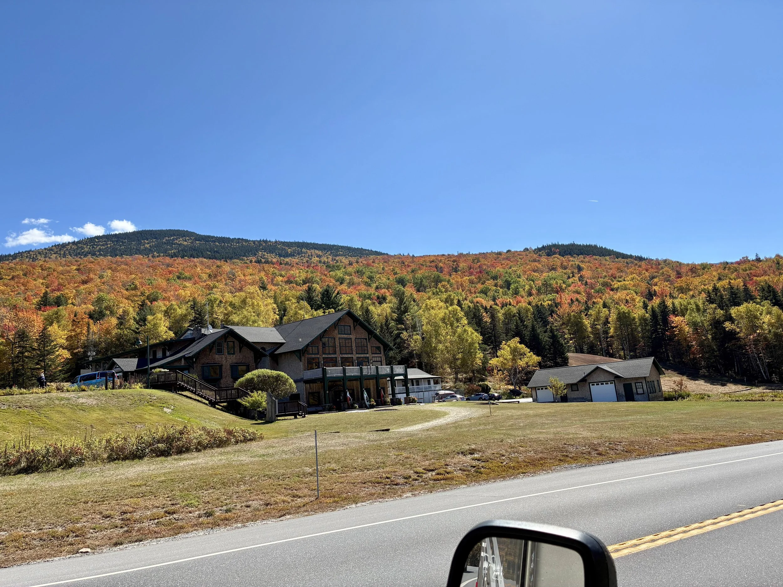 A mountain lodge with a brilliant red foliage-covered mountainside.