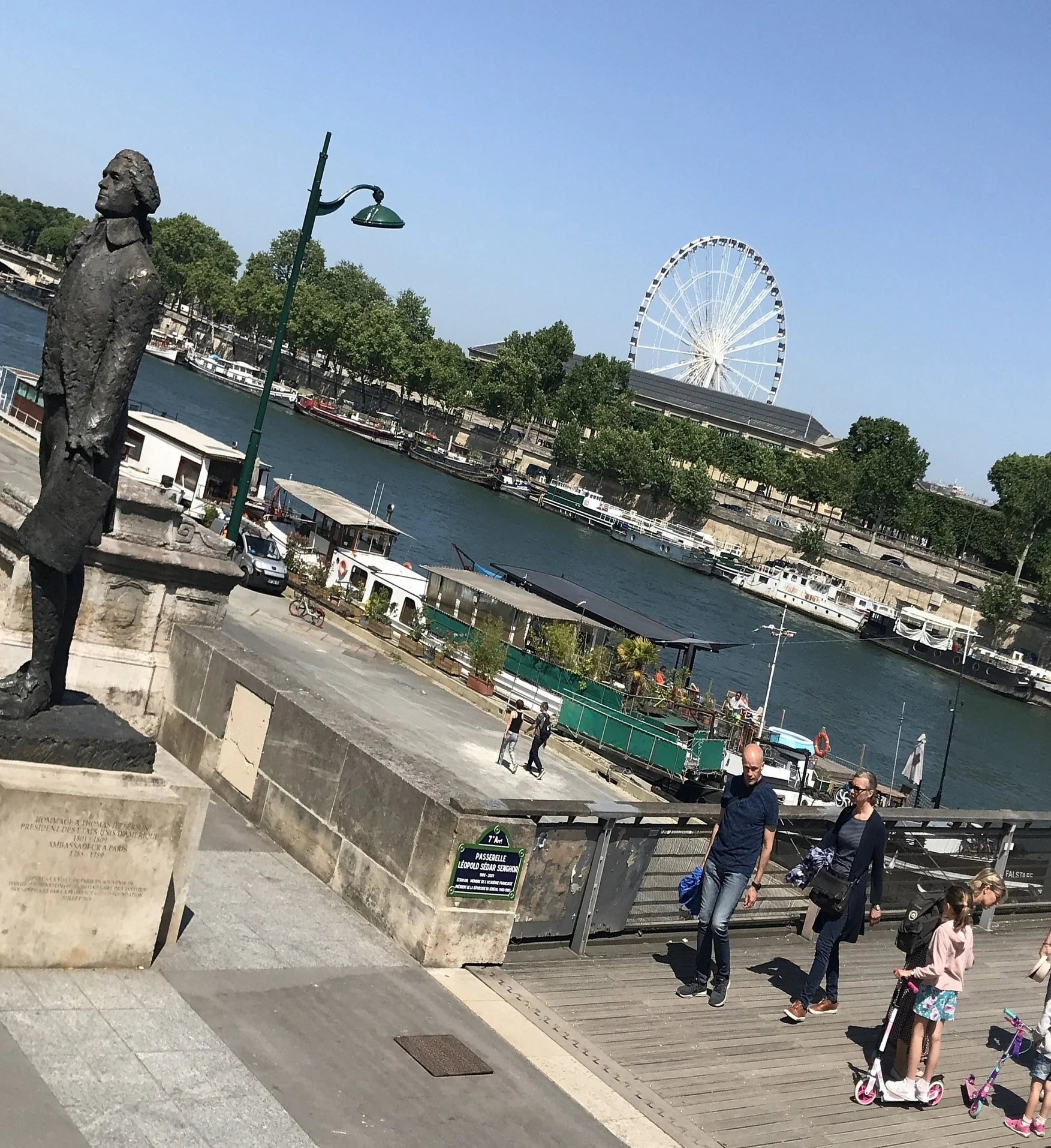 The Thomas Jefferson statue on the Seine embankment, with the river and a Ferris wheel.