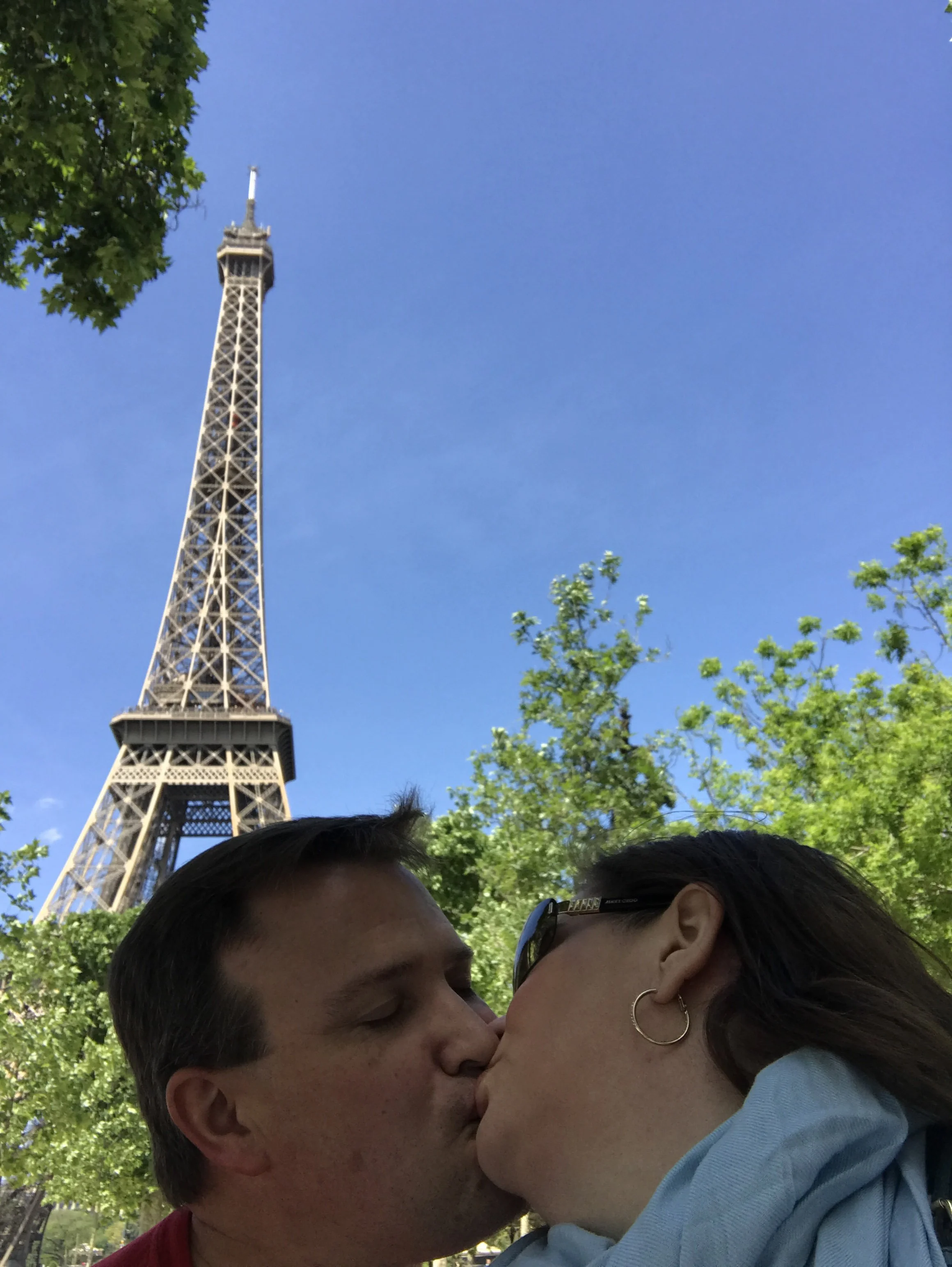 A couple kissing in front of the Eiffel Tower.