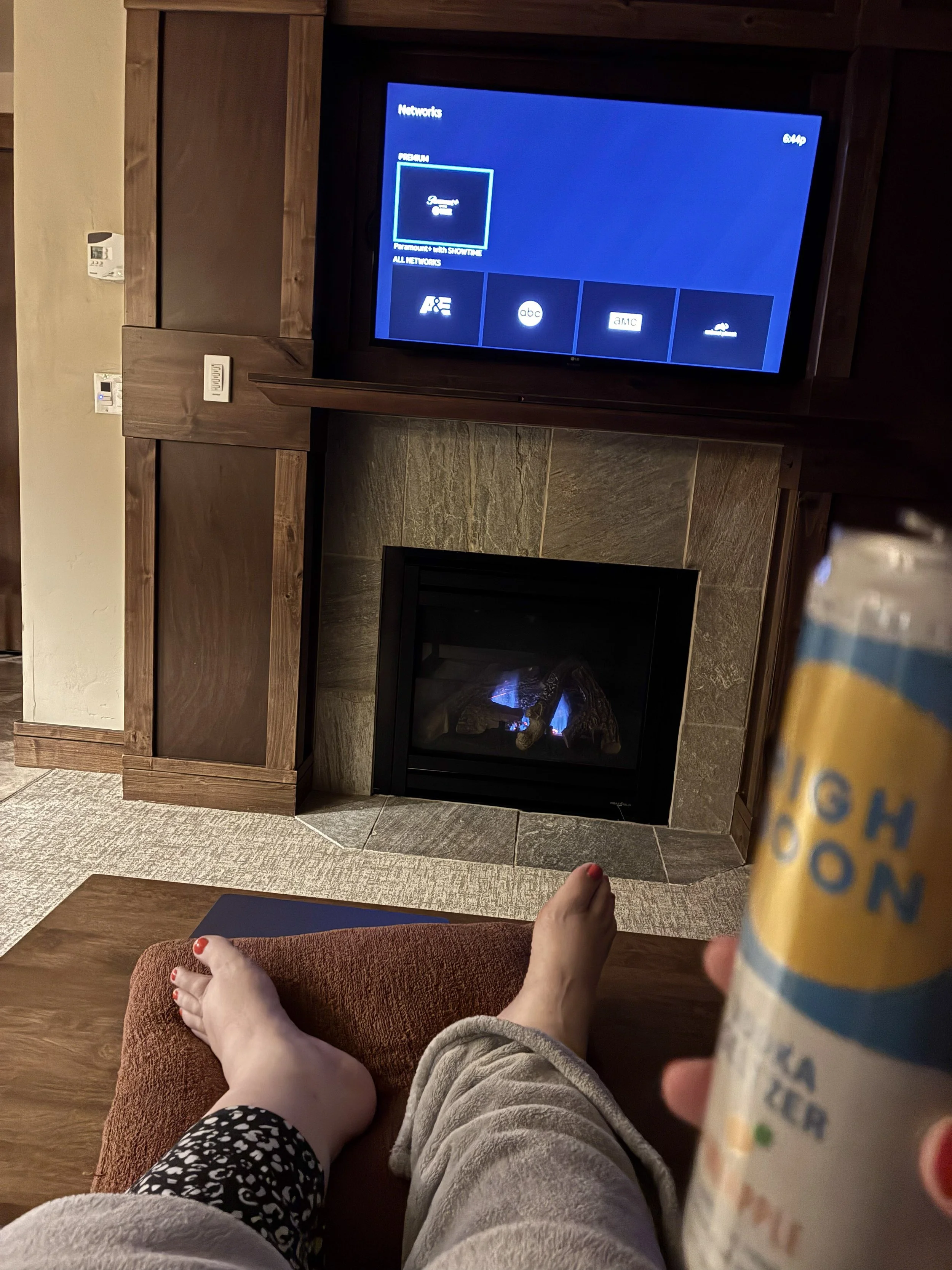 Feet up by the fireplace with a drink.