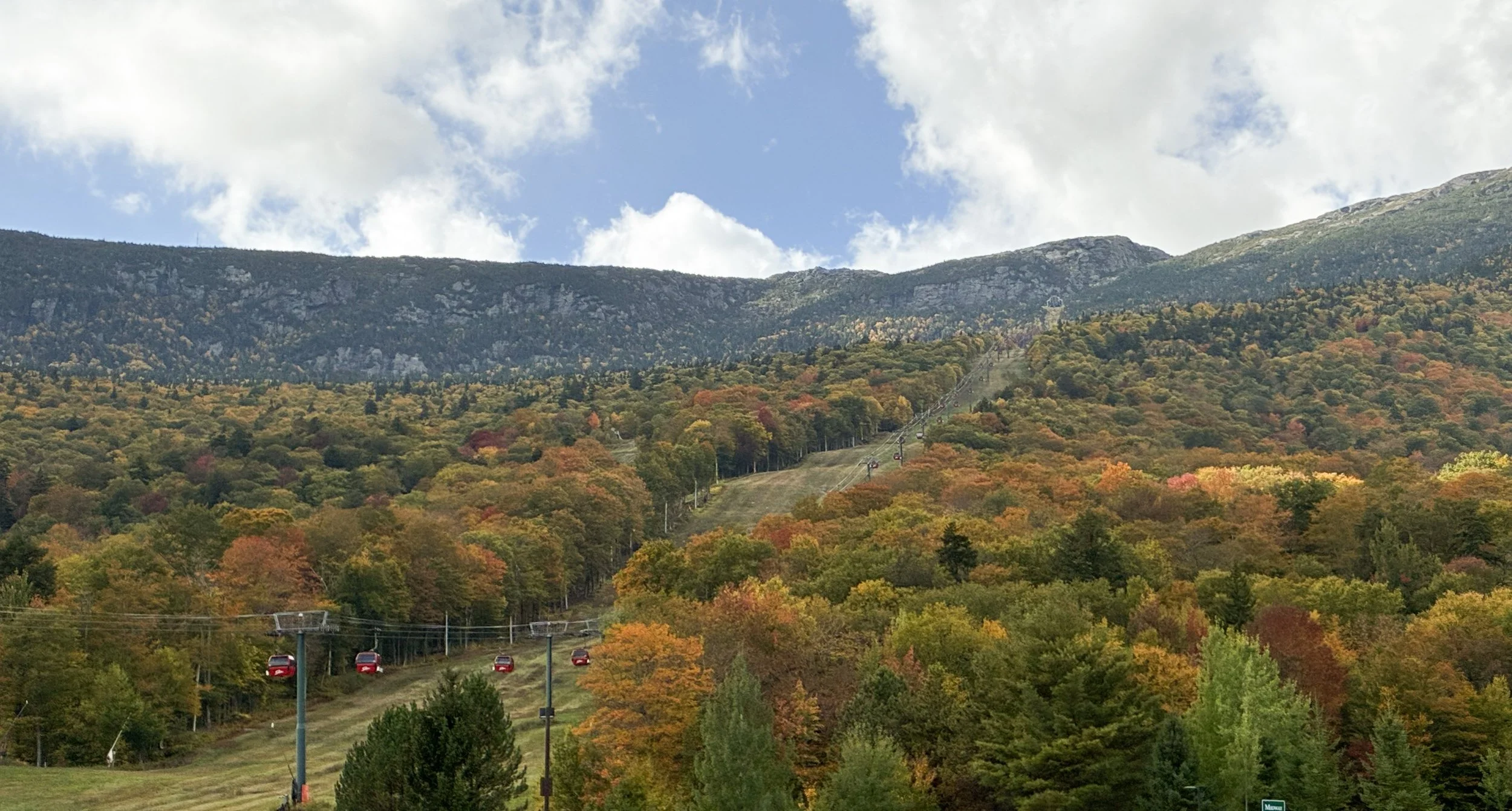 Red gondolas at Stowe Mountain Resort with a colorful fall mountainside.
