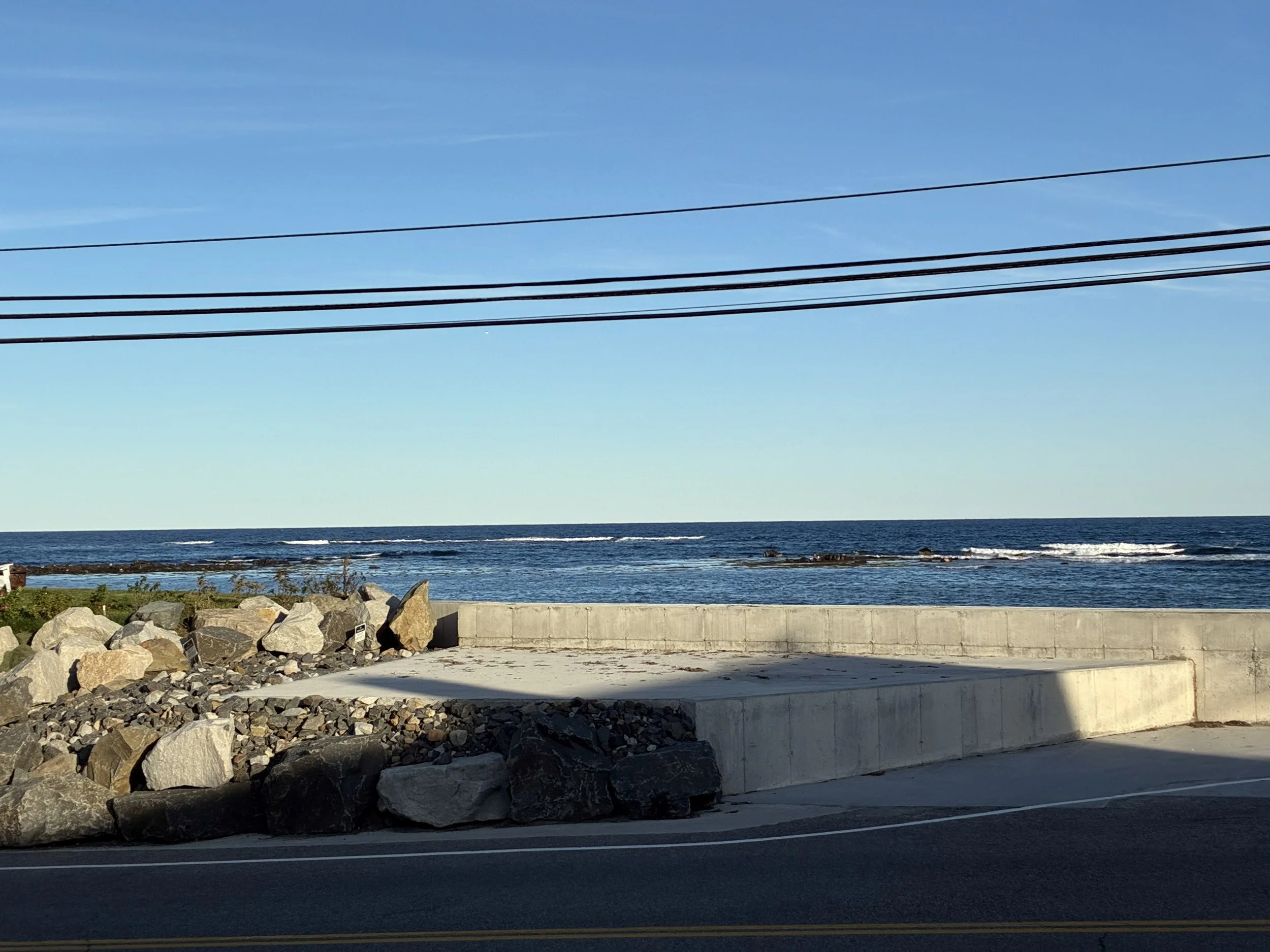 Rocky coastline with a stone seawall and ocean waves.