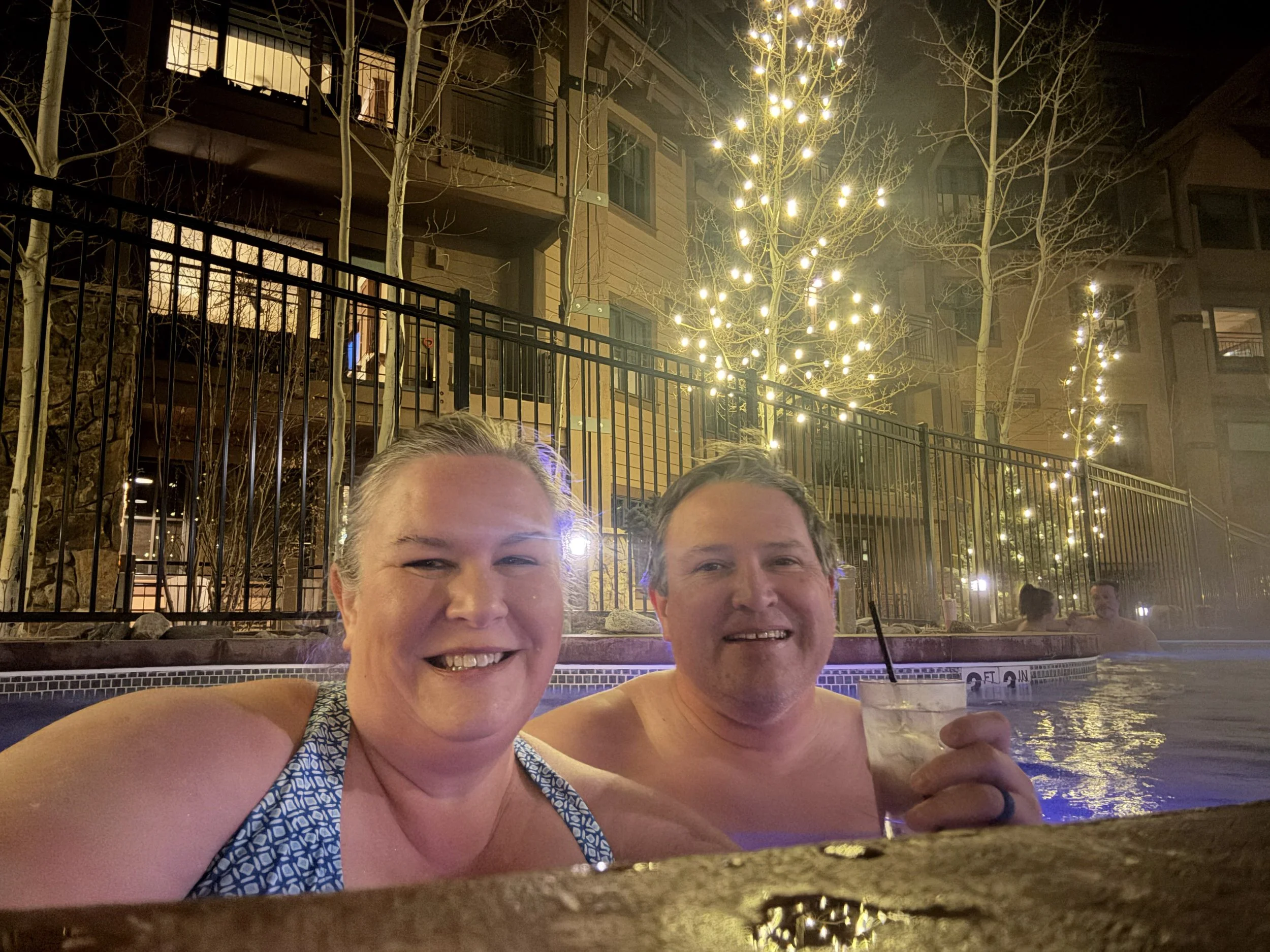 The author and her husband in the outdoor hot tub at night under string lights.