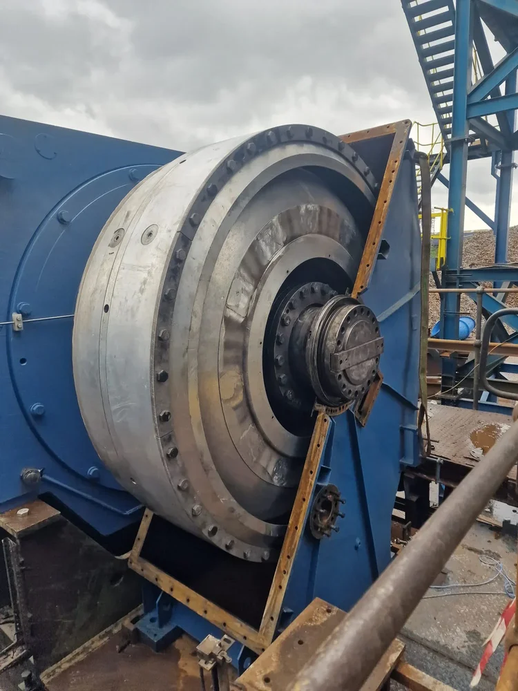 Exposed circular mechanical assembly on a blue industrial machine during site work