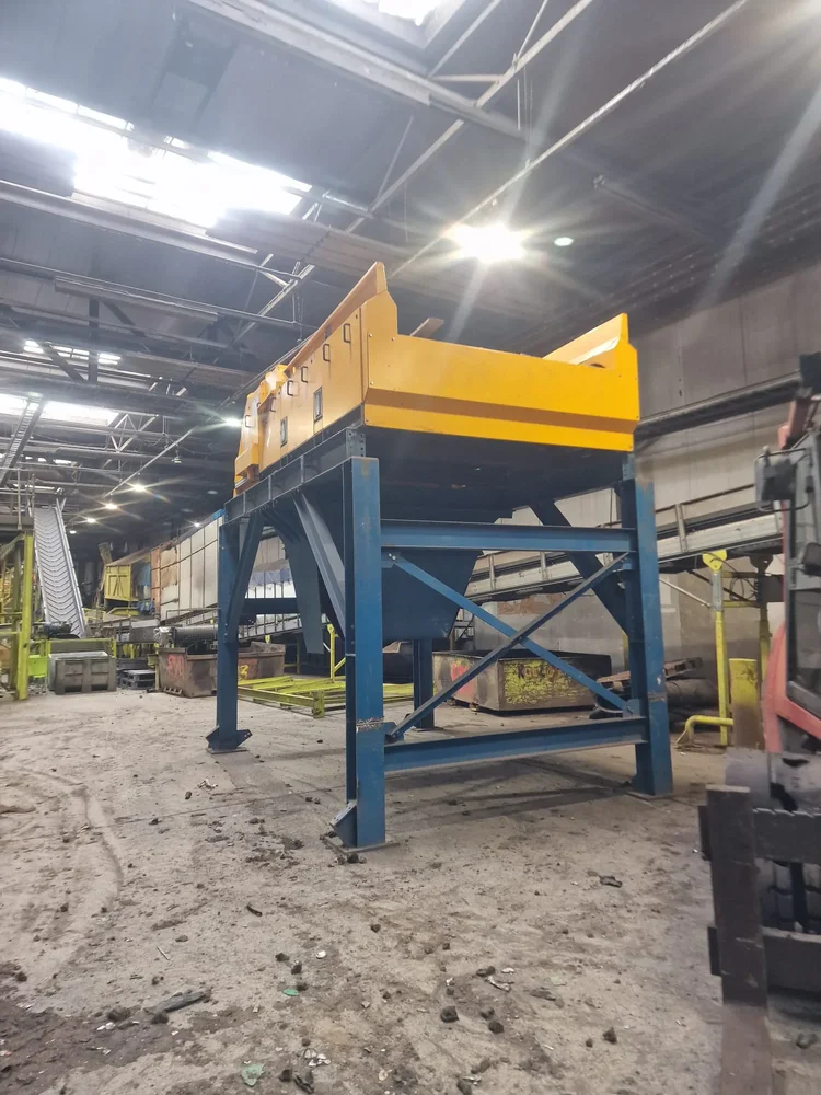 Yellow processing equipment mounted on a blue steel support frame inside an existing industrial building
