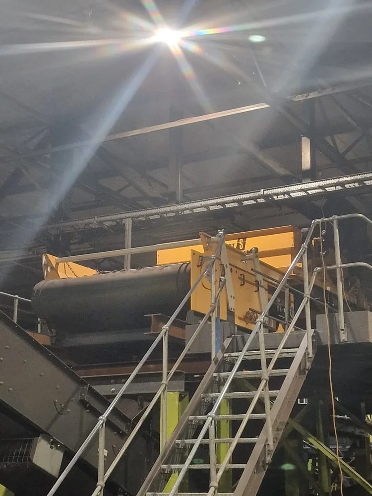 Yellow processing equipment and belt conveyor alongside a metal access stairway