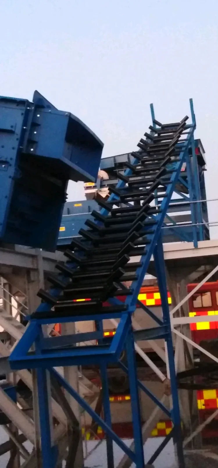 Blue conveyor support structure and troughing rollers during fabrication or installation