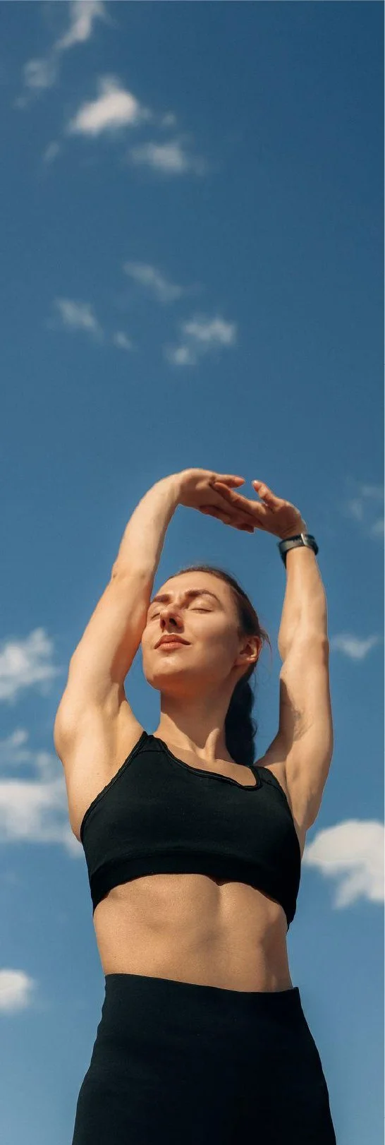 Woman stretching outdoors under a blue sky