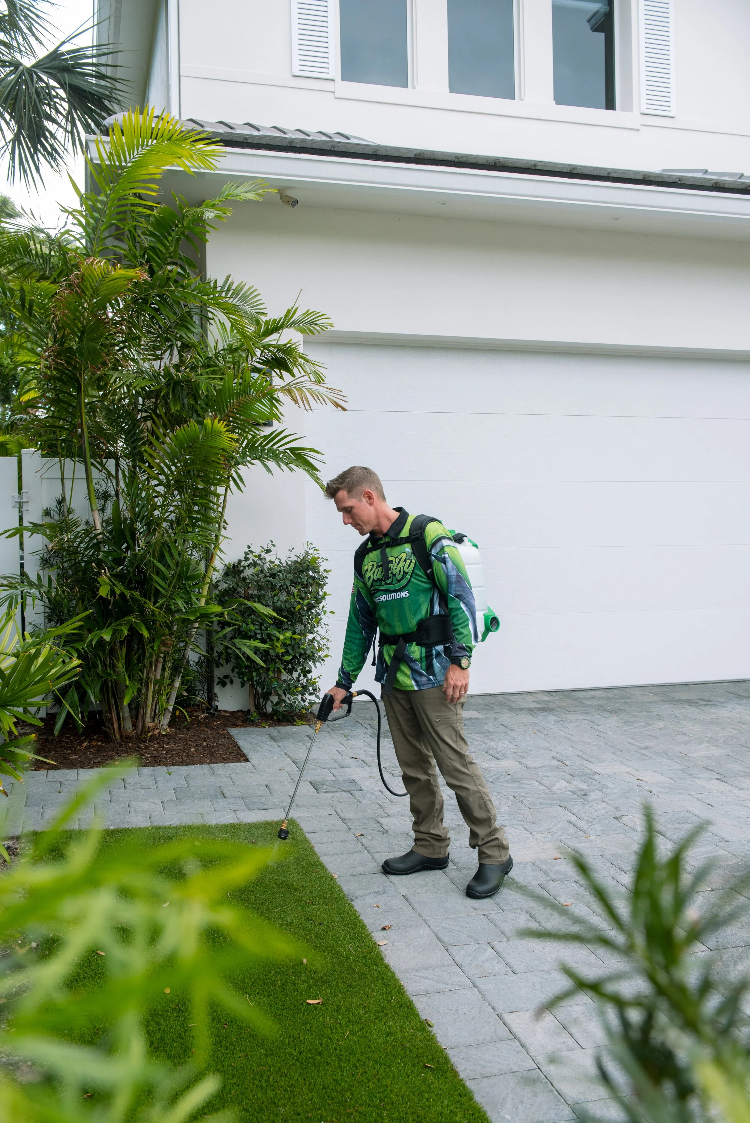 Buggify technician spraying a lawn edge beside a driveway