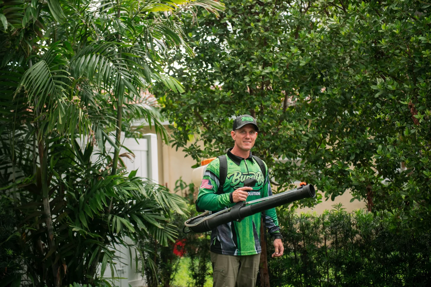Buggify technician smiling with a mist-blower in garden greenery