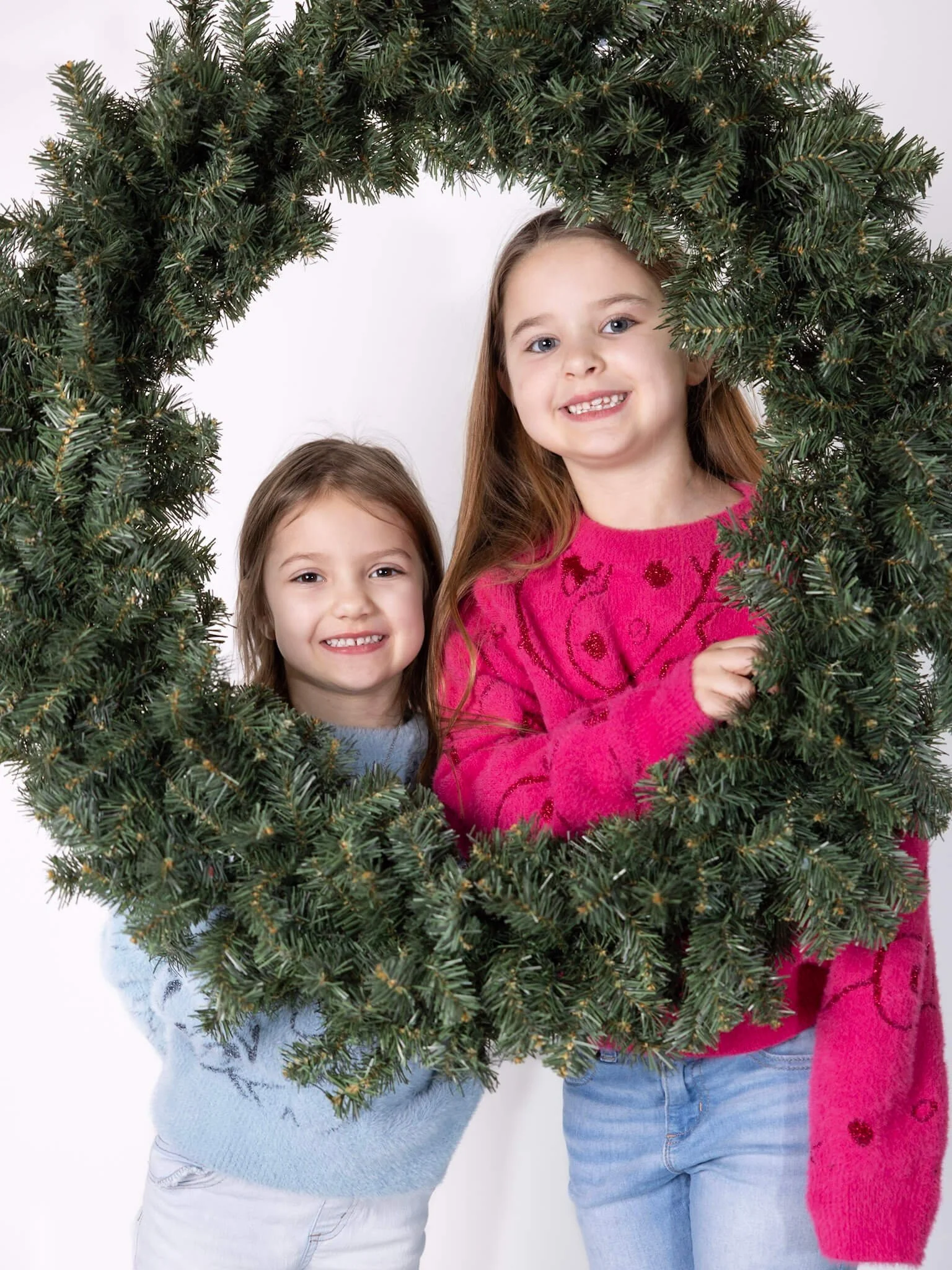 Children framed by a holiday wreath photo booth backdrop