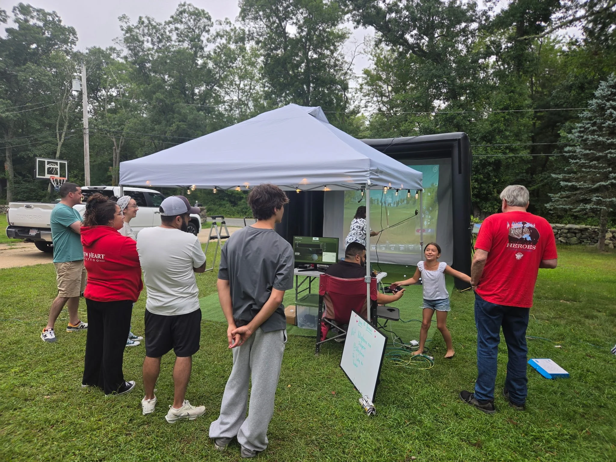 Guests enjoying The Rolling Tee mobile golf simulator at an outdoor event