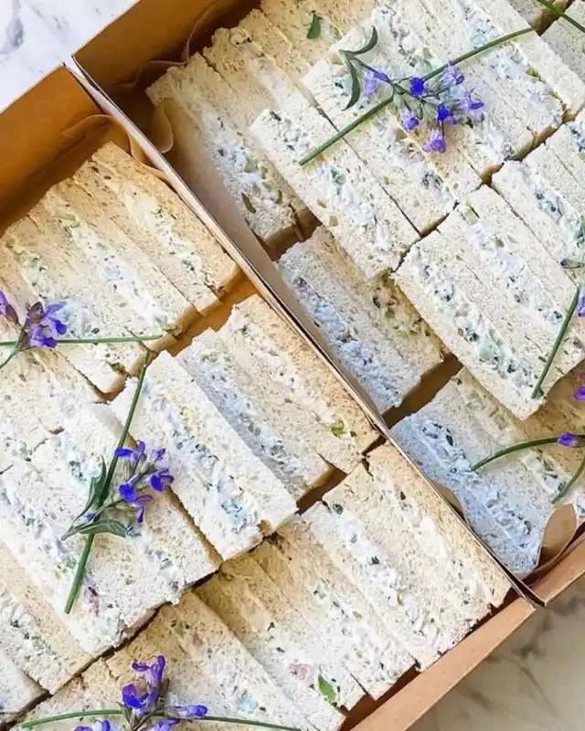 Boxes of finger sandwiches topped with chives and sage flowers
