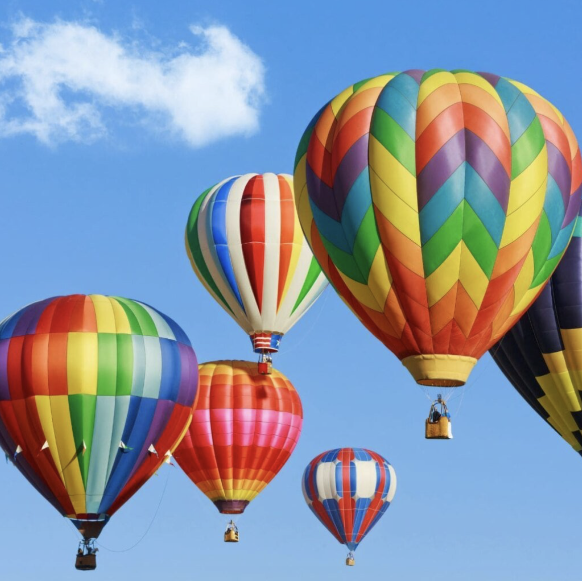 Colorful hot air balloons rising into a blue sky