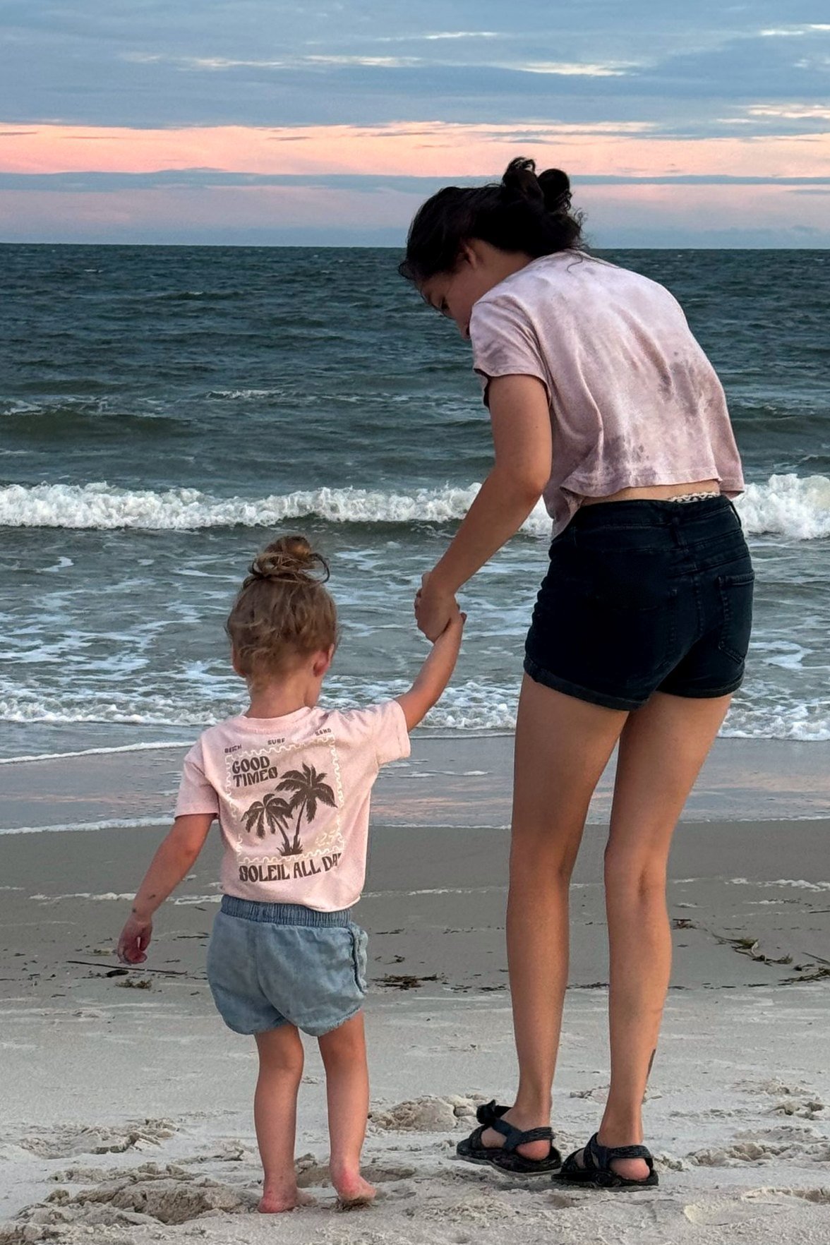 Dixie walking with her oldest daughter on the beach at sunset