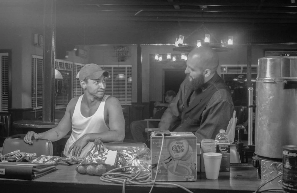 Cast members talk between takes at the motel counter