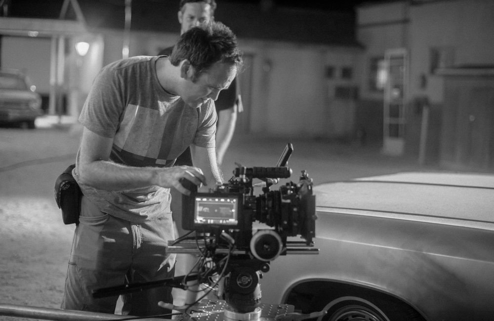 Camera department adjusts the RED Dragon beside the picture car
