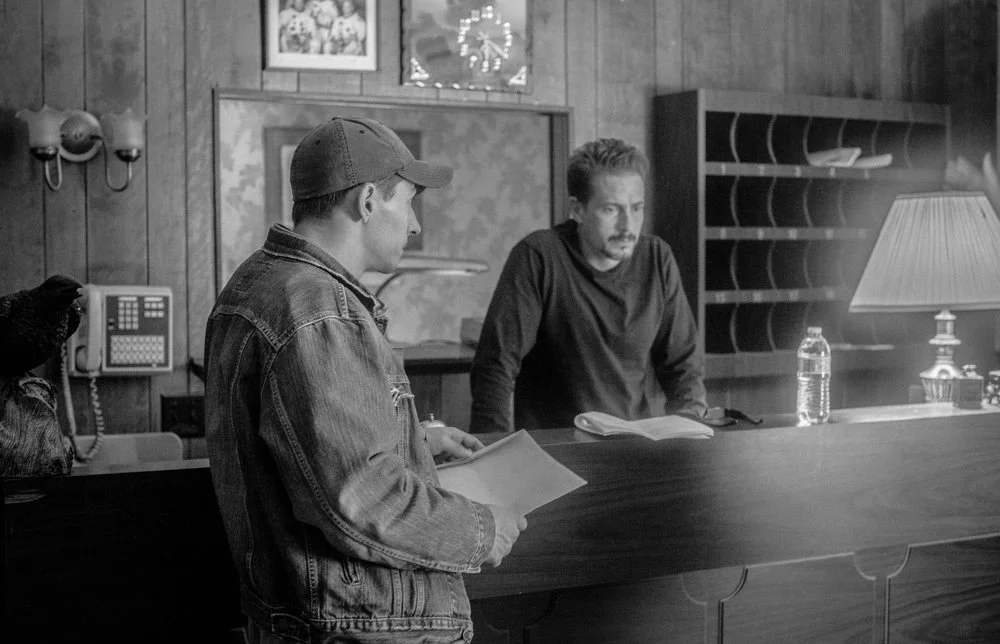 Actors rehearse a scene across the motel front desk