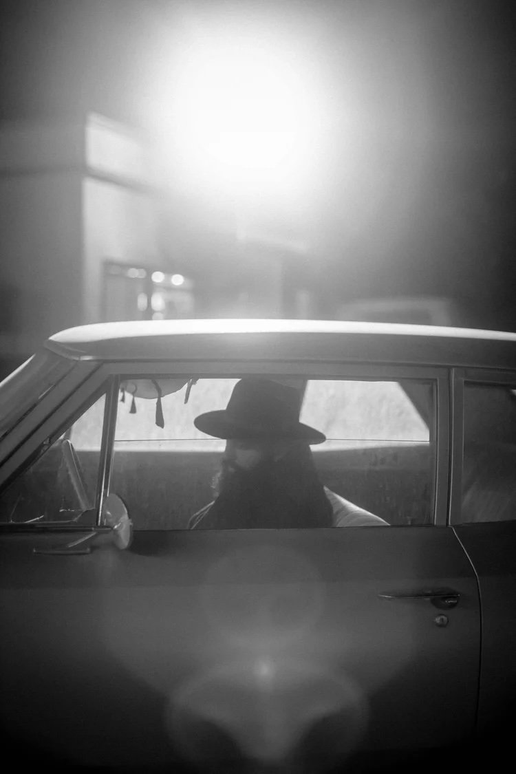 The mysterious guest framed inside the picture car under hard backlight