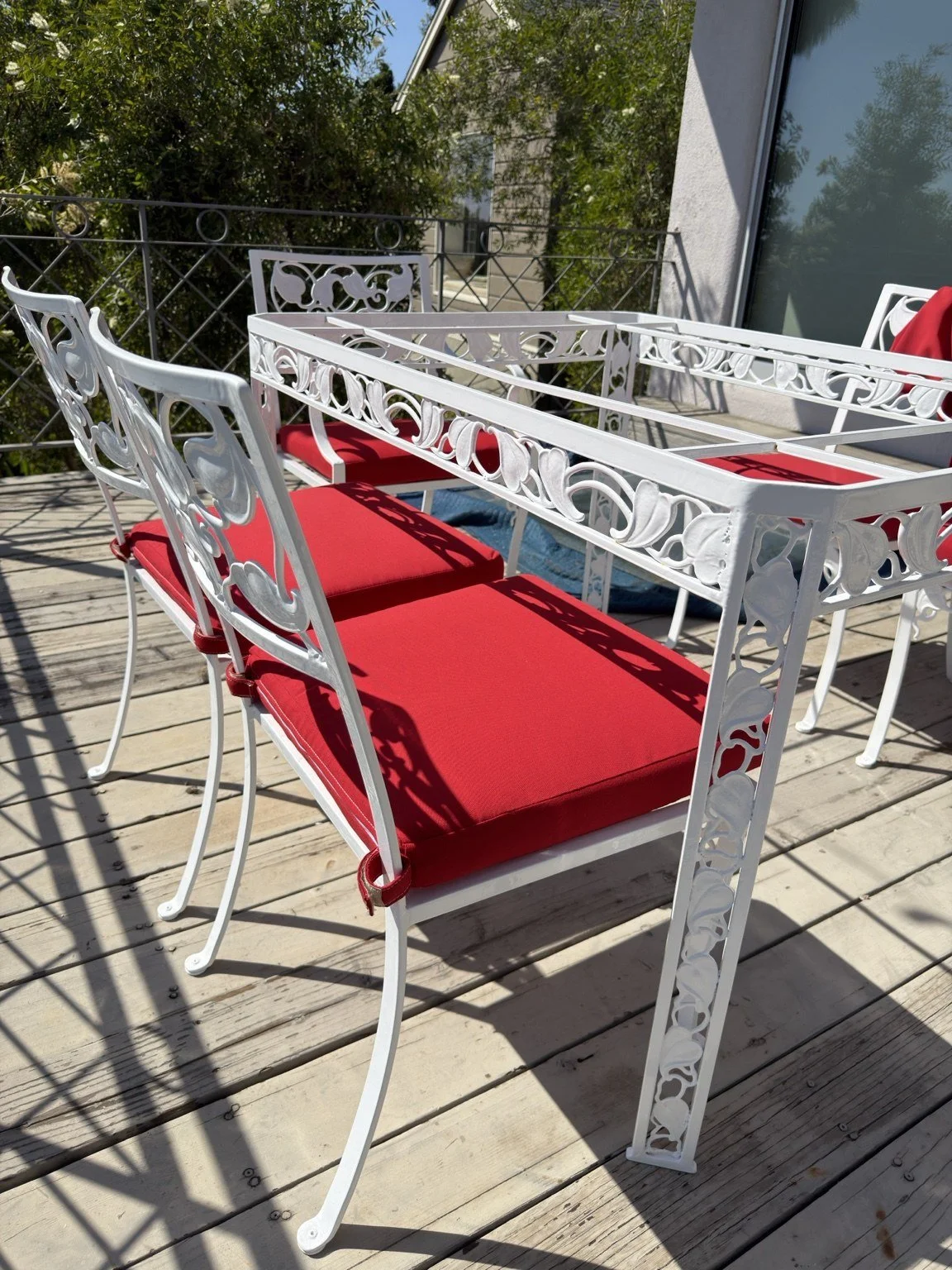 Custom red outdoor seat cushions with fabric ties securing them to refinished white metal chairs