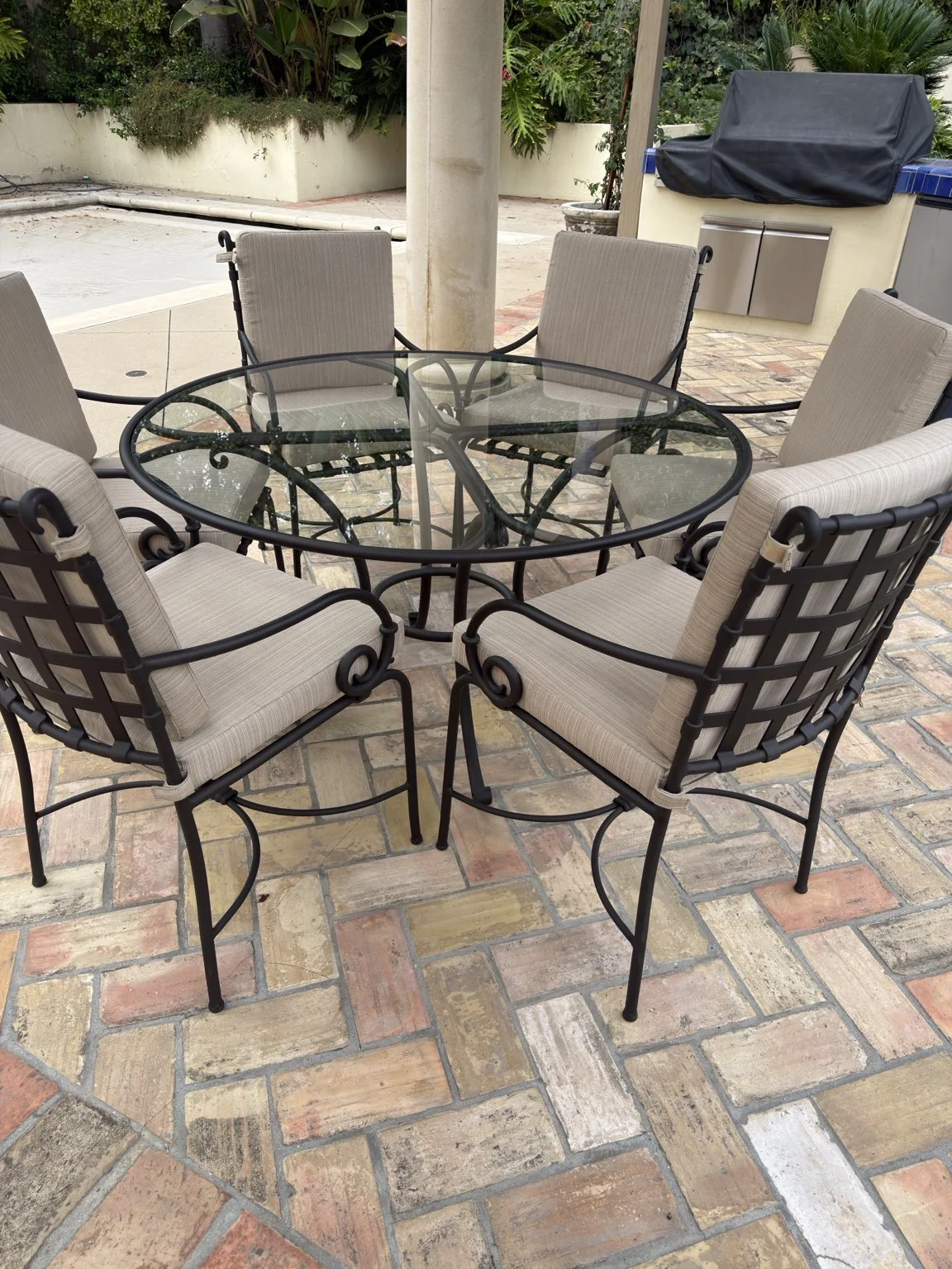 Outdoor dining set with a round glass table and fitted cream cushions