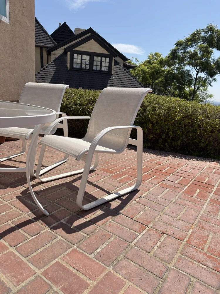 White framed sling patio chairs on a brick terrace in Beverly Hills