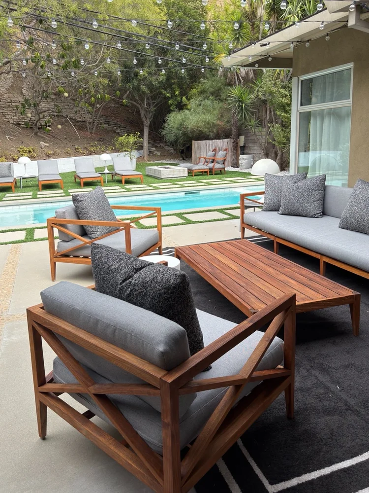 Wood lounge chairs and sofa with gray cushions beside a Beverly Hills pool