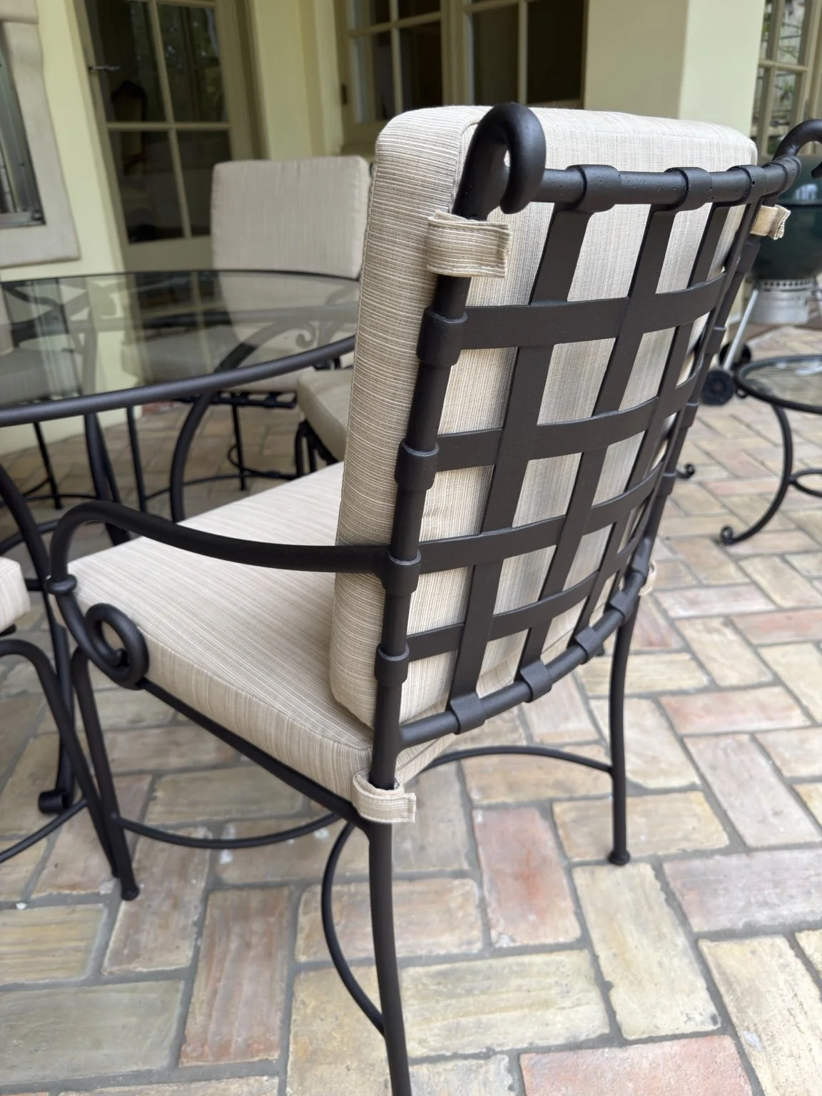 Close view of a fitted cream back cushion on a black metal patio chair