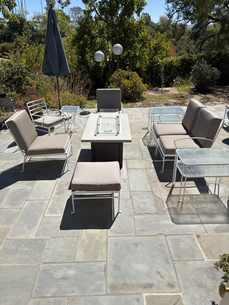 Outdoor dining table and gray cushioned chairs on a Beverly Hills stone patio