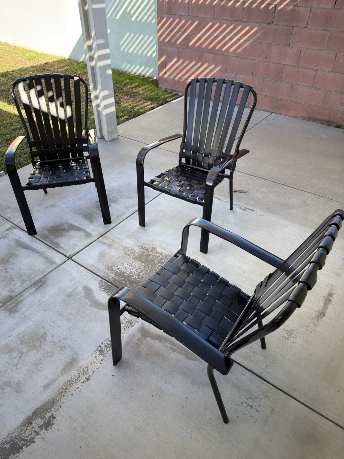 Black restored patio dining chairs with vertical back straps and woven seats in Pasadena