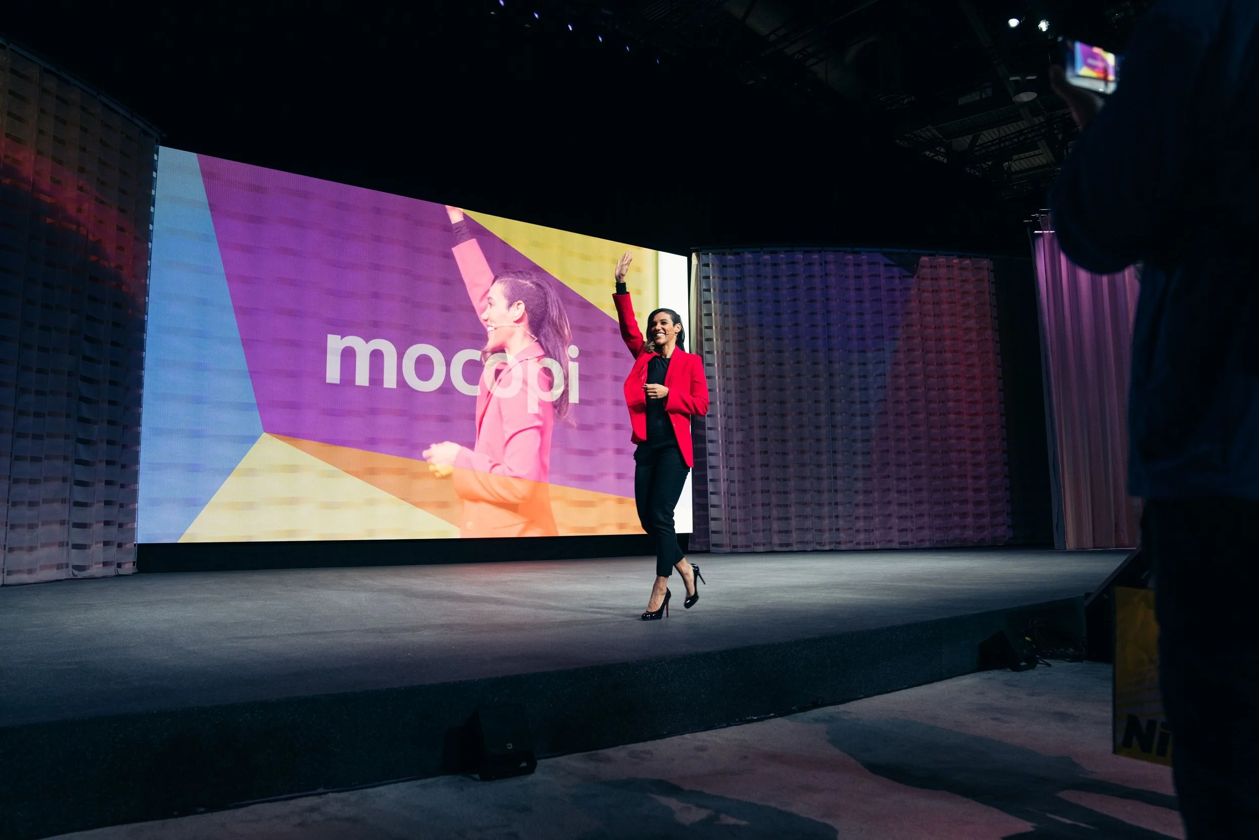 Dionna Chambers smiling and raising one hand on stage during a Sony Mocopi presentation