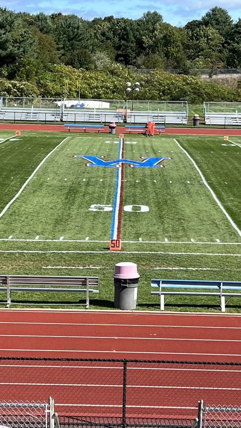 Football field 50-yard line with team logo painted at midfield