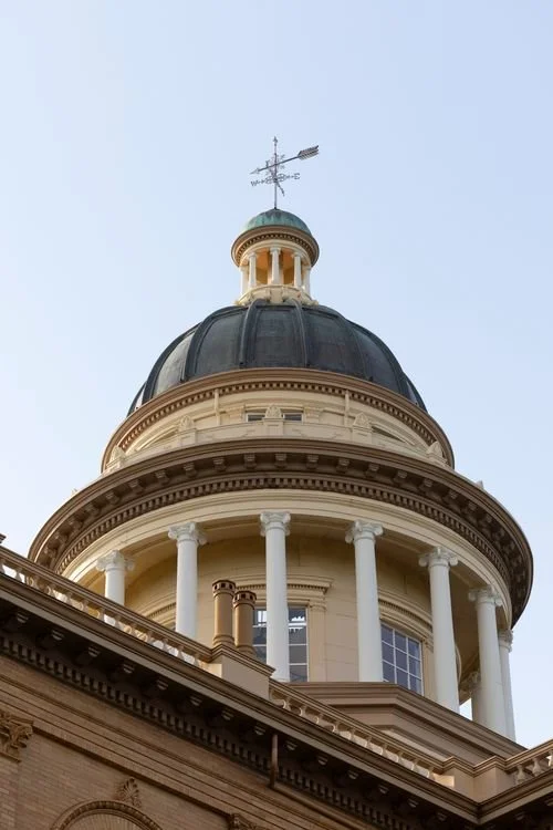 Dome and columns of a civic courthouse building against the sky.
