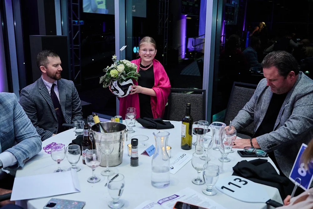 A young guest holding a custom soccer-ball vase centerpiece won at the gala auction