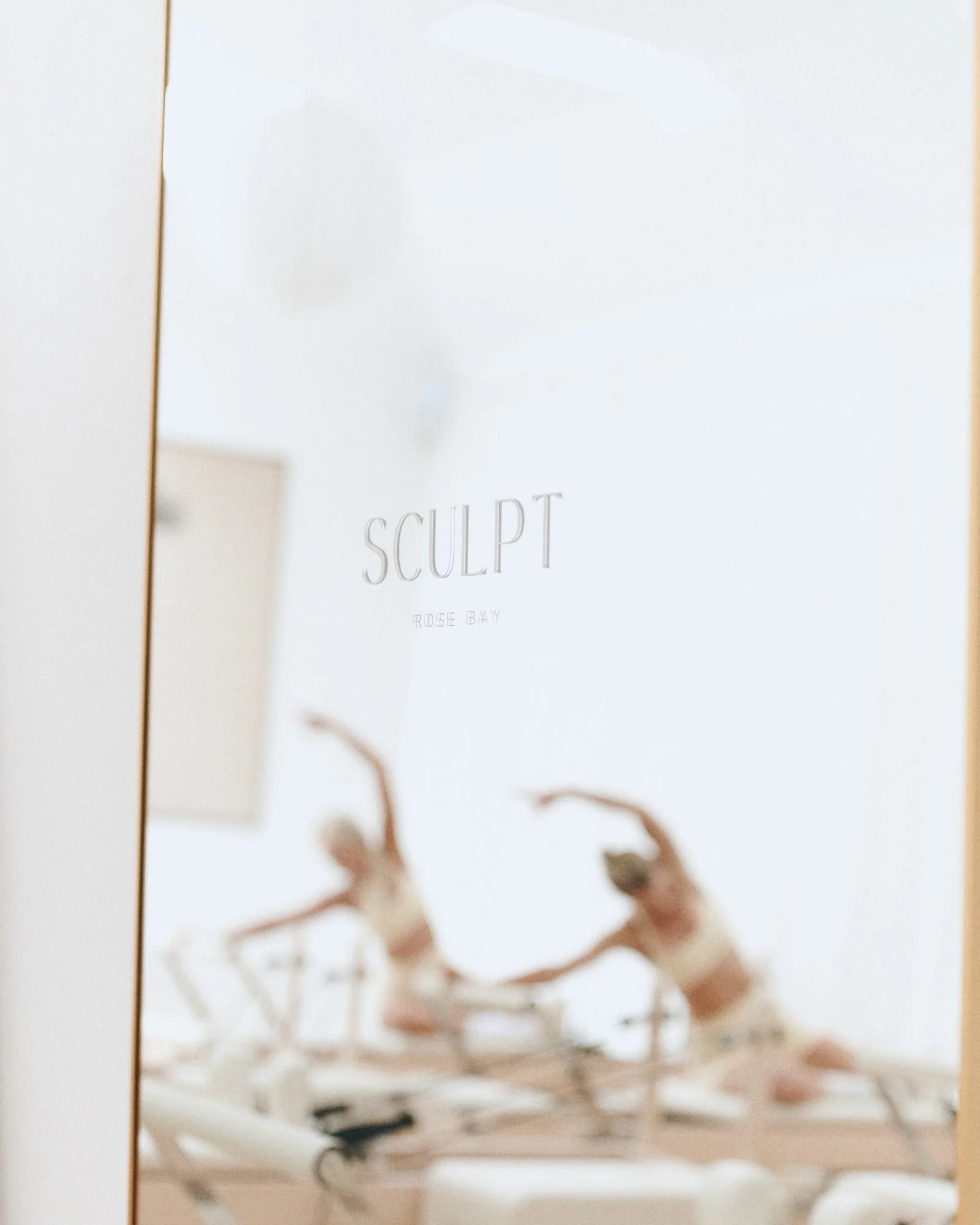 SCULPT Rose Bay etched on the mirror, with a class reflected behind