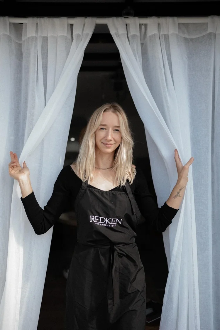 Kateryna at the studio entrance, between the white curtains