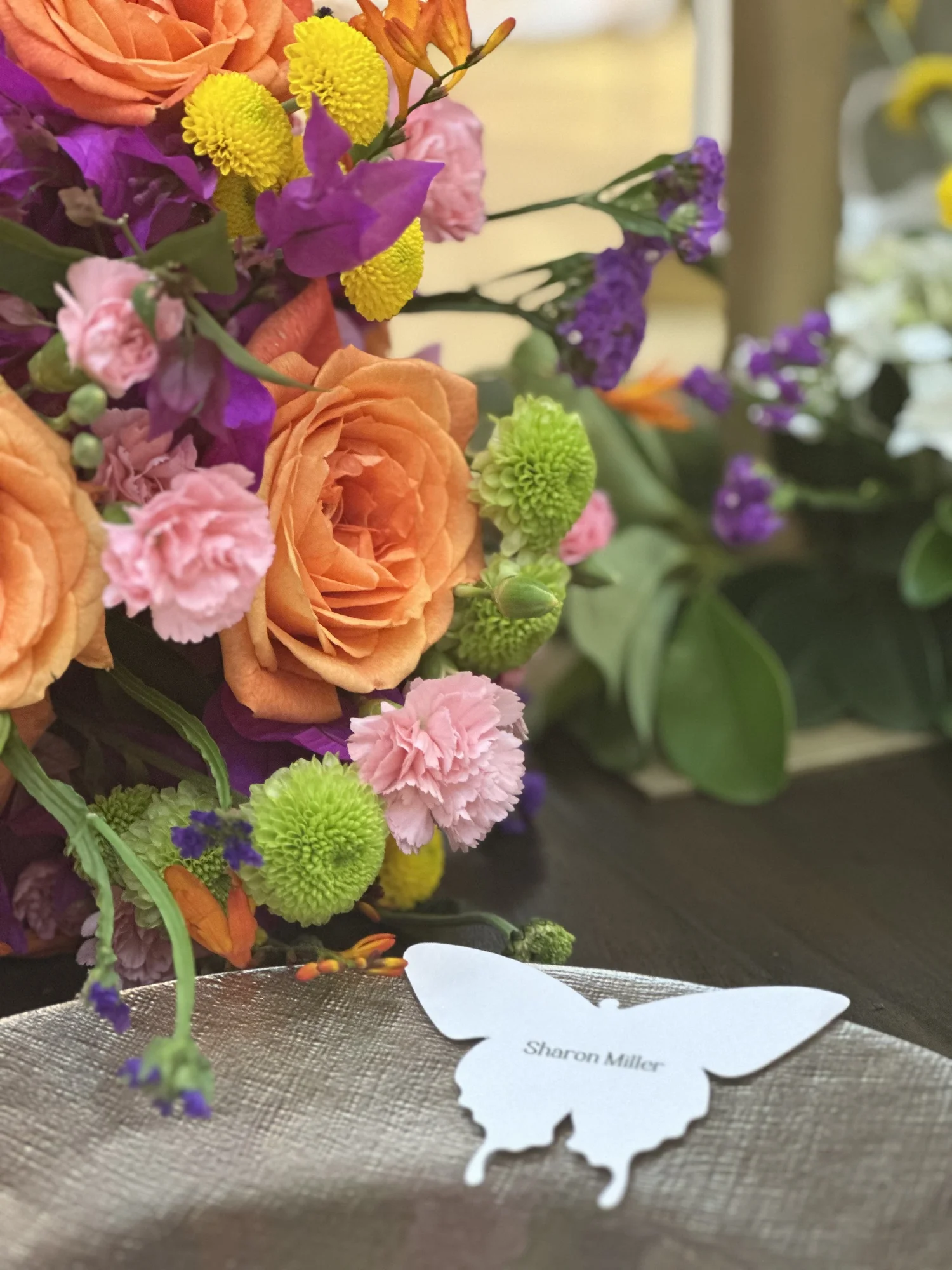 Detalle de rosas y flores en tonos rosa y naranja con una mariposa de papel