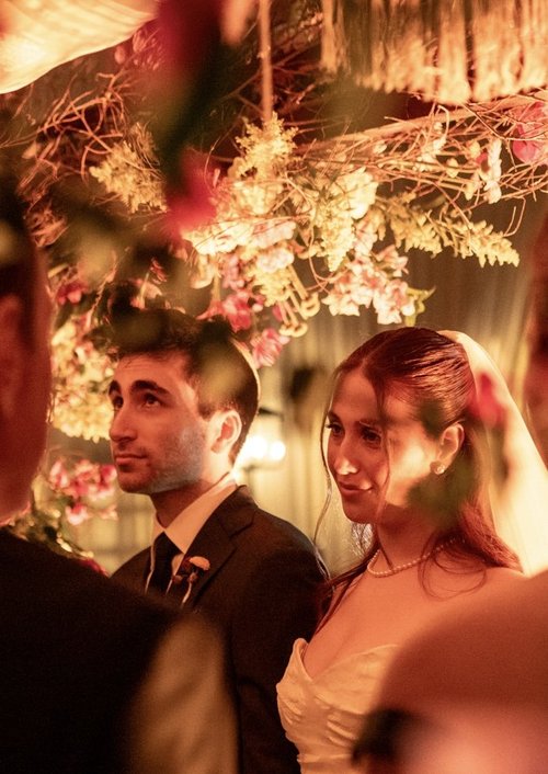 Sharon y Josh bajo la jupá cubierta de flores rosadas