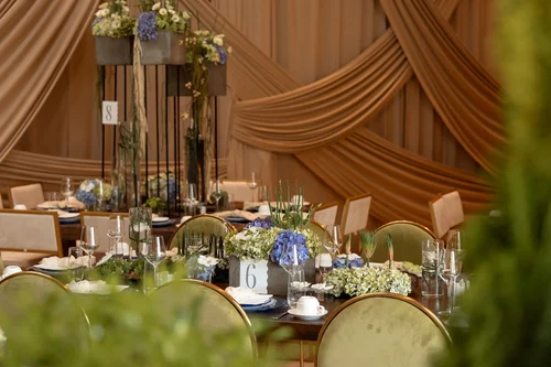 Mesa con drapeados, sillas verdes y arreglos de flores