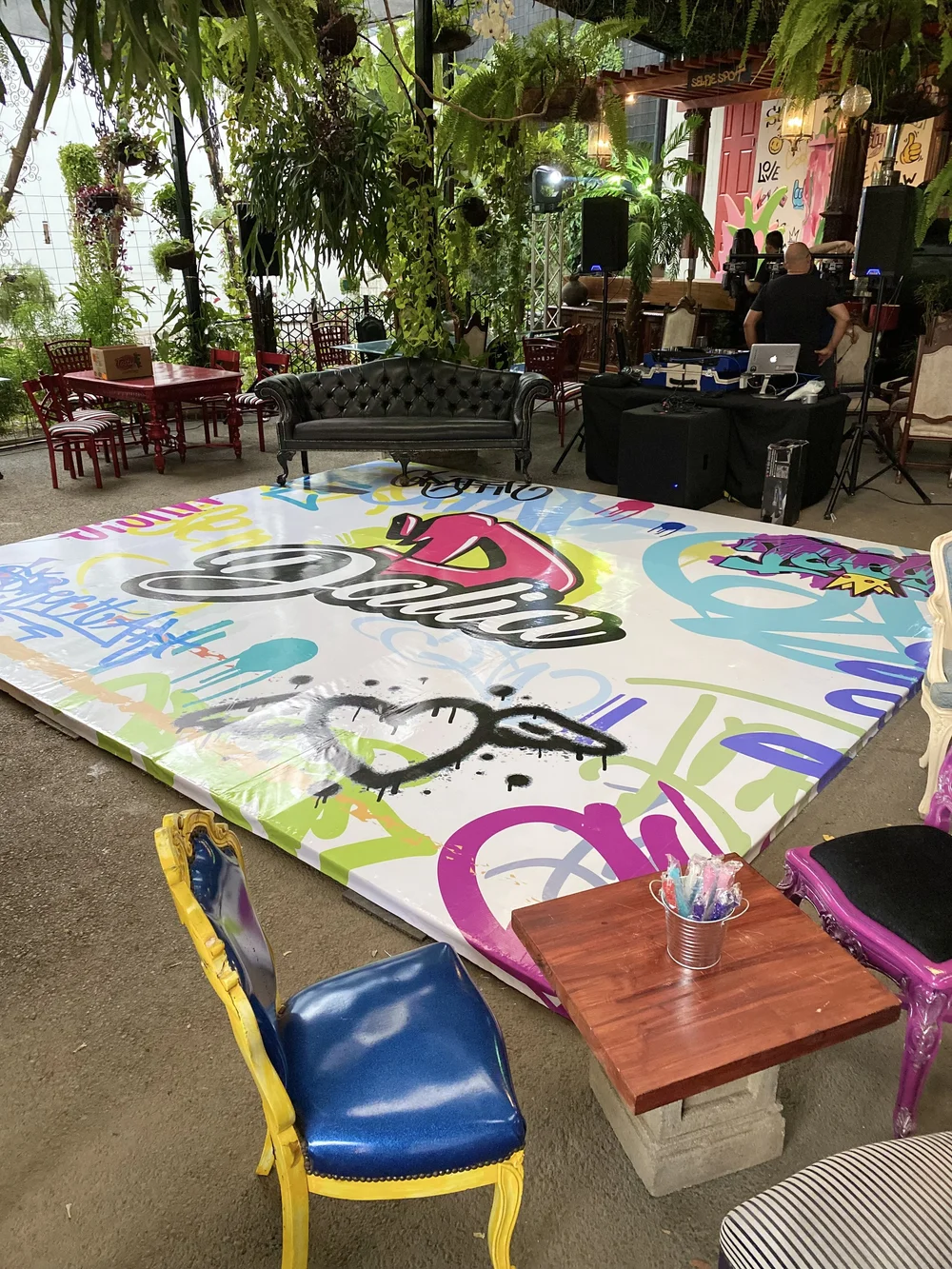 Tarima con grafiti de Dalia, sillas de colores y un sofá en el patio del local