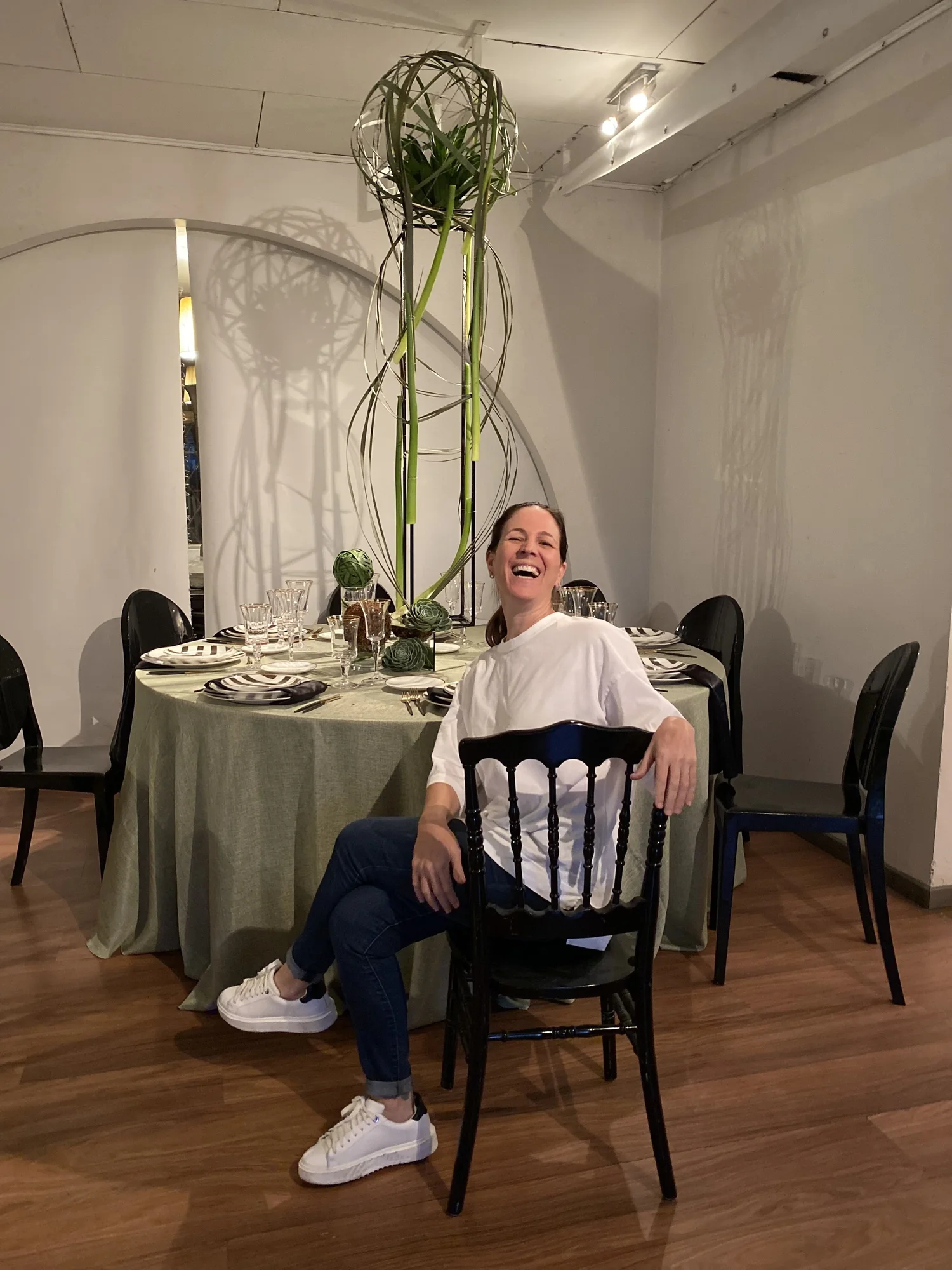 Matías ríe sentado a la mesa de su bar mitzvá, con velas altas y arreglos verdes