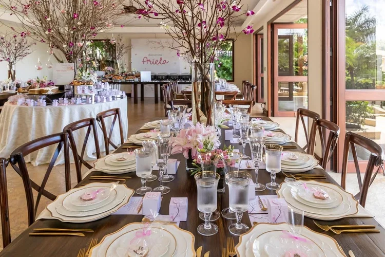Mesa de Cherry Blossom Baby: vajilla blanca con filo dorado, cubiertos dorados y ramas de cerezo en flor