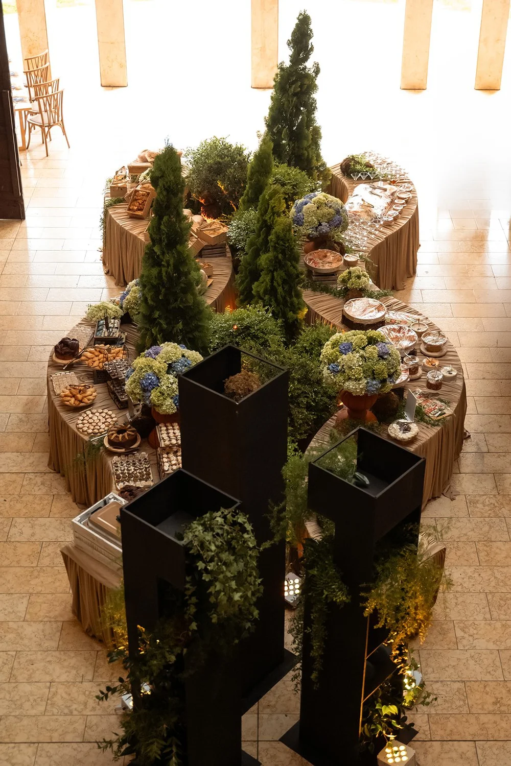 Vista aérea del buffet con cipreses, hortensias azules y maceteros negros en el salón