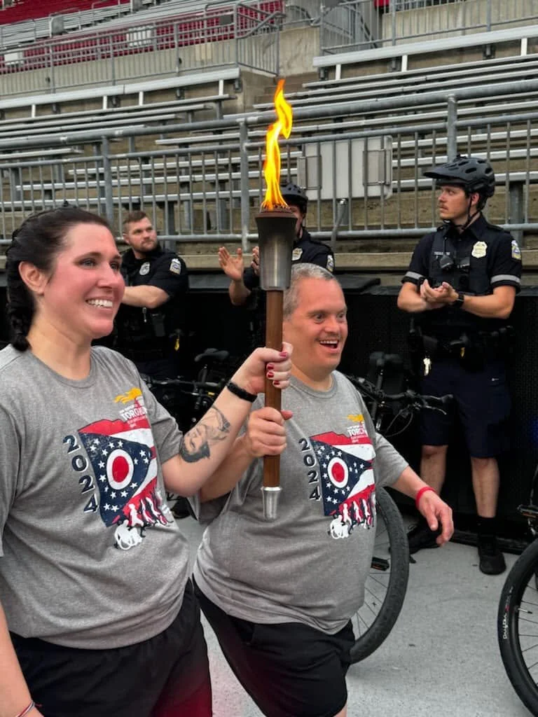 Flash athletes carrying the Flame of Hope torch alongside local officers.