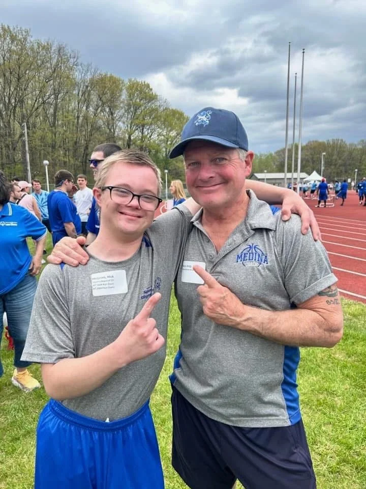 A Flash athlete and coach arm in arm at the track.